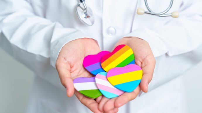 プライドフラッグを大切に手にする医師